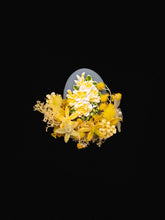 The Freesia Birth Flower Ring by CAMELLIA is a stunning arrangement of yellow and white flowers with lush greenery and dried preserved flowers set against a black background.